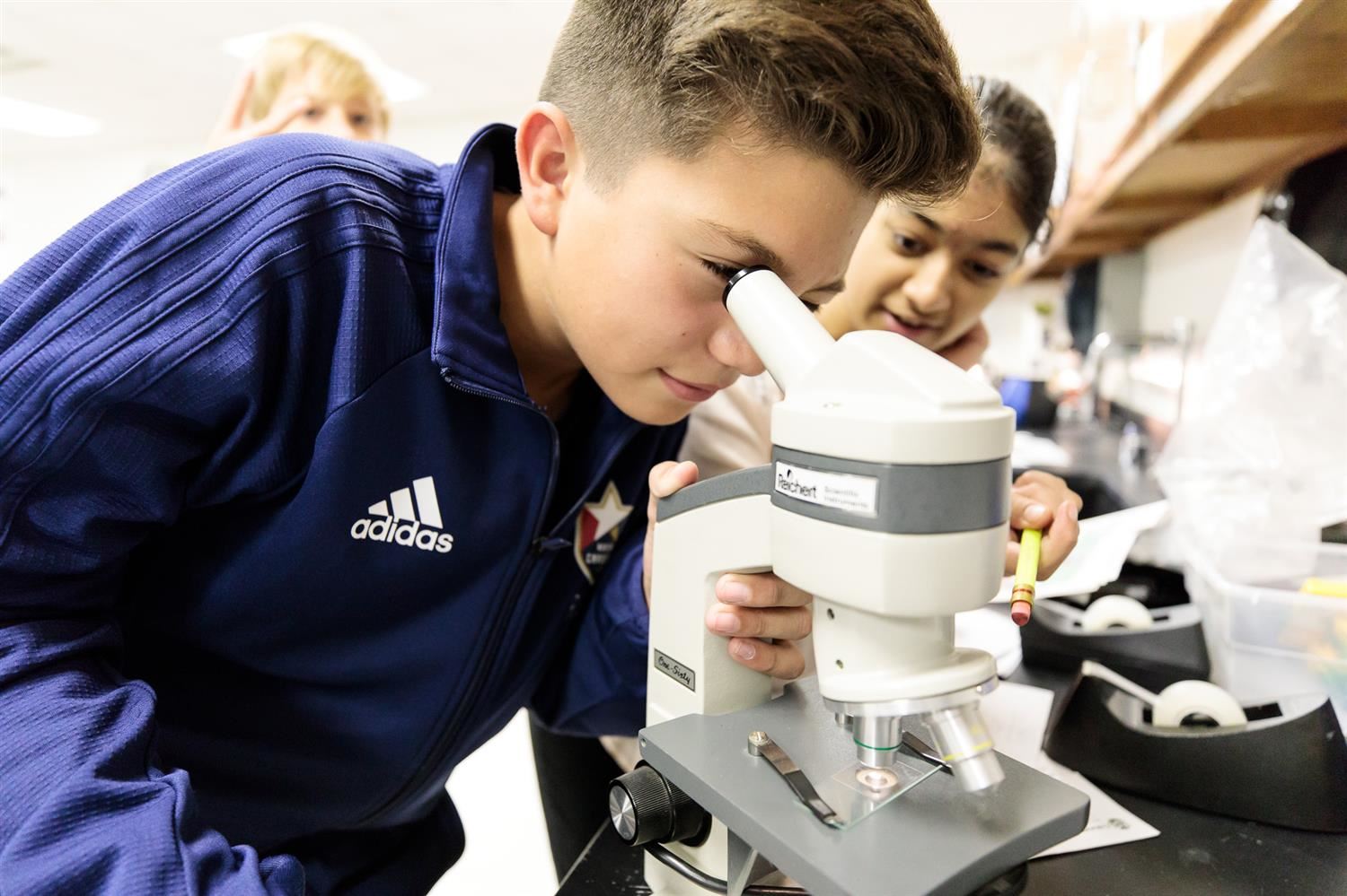 Student at Martin Magnet Middle School looks into microscope. 